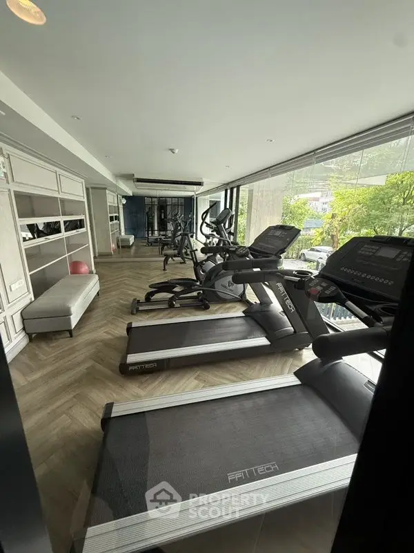 Modern gym with state-of-the-art equipment and large windows for natural light.