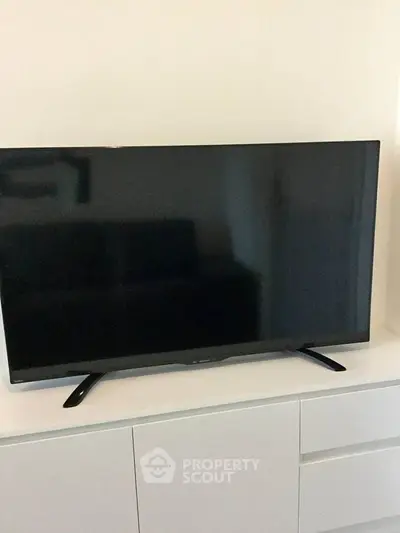 Modern living room with sleek flat-screen TV on white cabinet