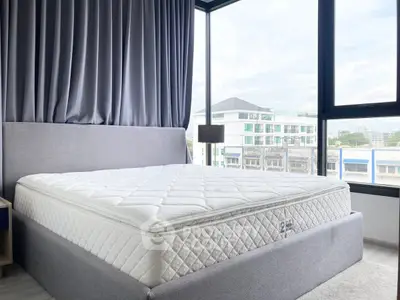 Spacious bedroom with large windows and modern decor, offering a bright and airy atmosphere.