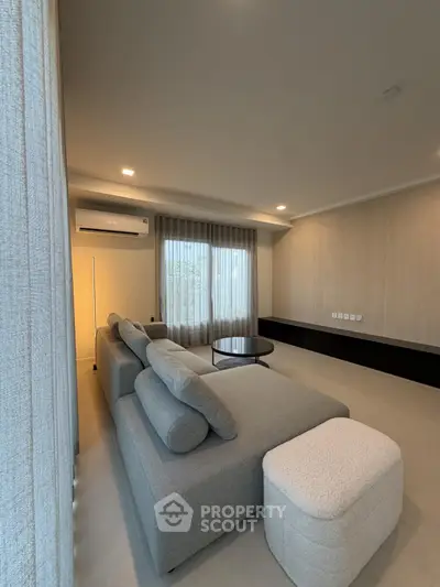 Spacious modern living room with elegant gray sofa and natural light.