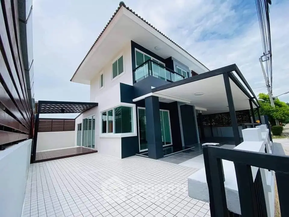 Modern two-story house with sleek design and spacious tiled patio, perfect for family living.