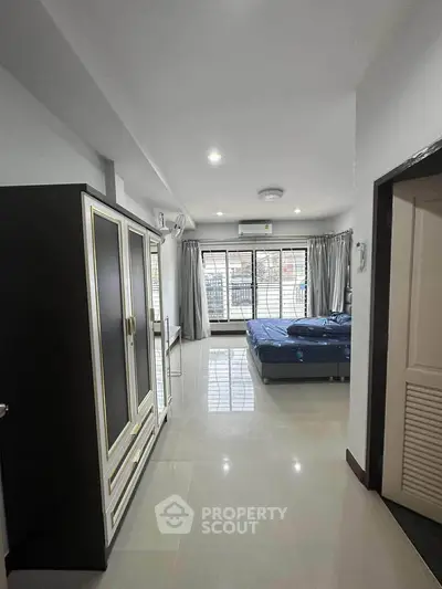 Spacious bedroom with large windows and modern furnishings in a stylish apartment.