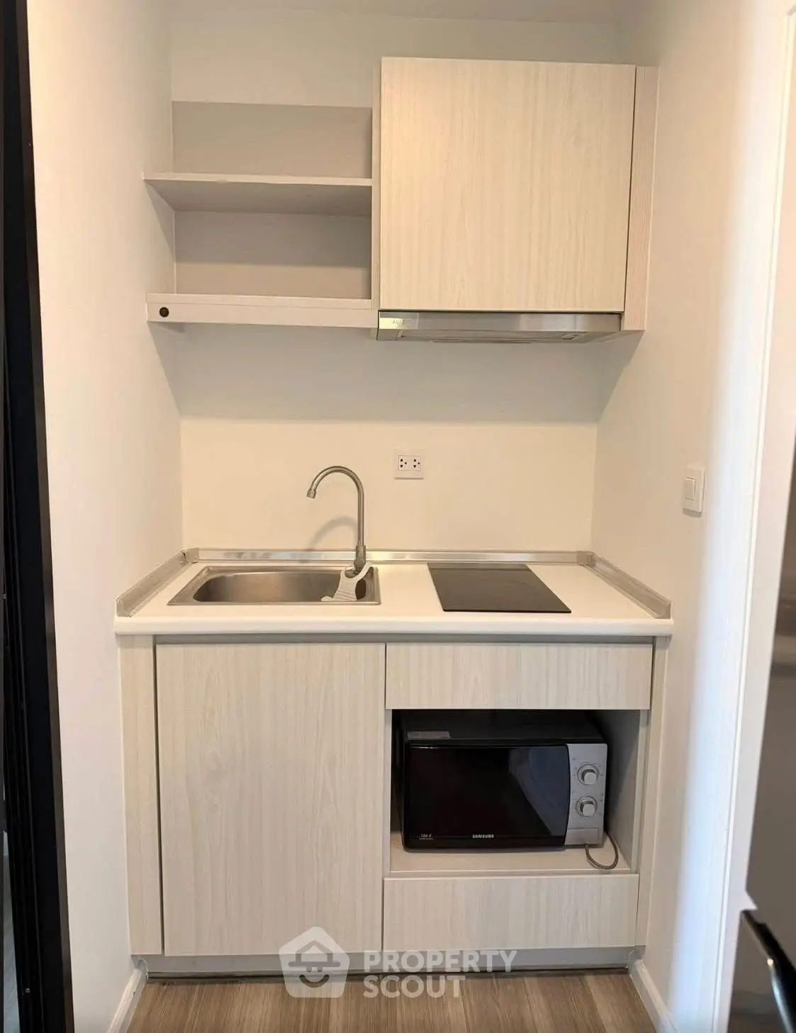 Compact modern kitchen with sleek cabinetry and built-in microwave, ideal for efficient urban living.