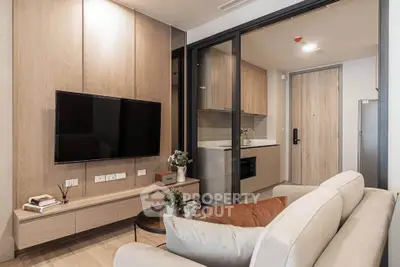 Modern living room with sleek TV setup and cozy kitchen area in stylish apartment.