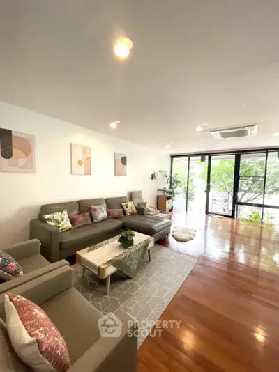 Spacious living room with modern decor and large windows overlooking greenery