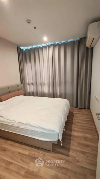 Cozy bedroom with wooden flooring and modern furnishings in a stylish apartment.