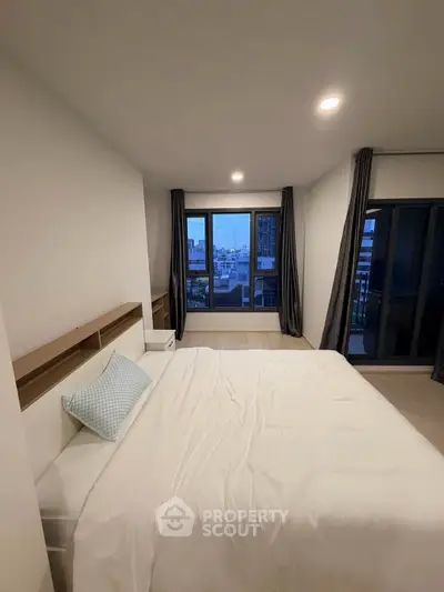 Spacious bedroom with city view and modern decor in a high-rise apartment.