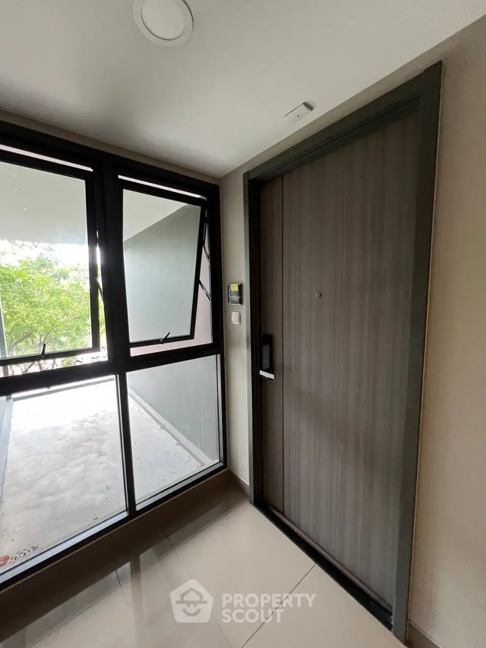 Modern apartment entrance with sleek door and large window offering natural light.