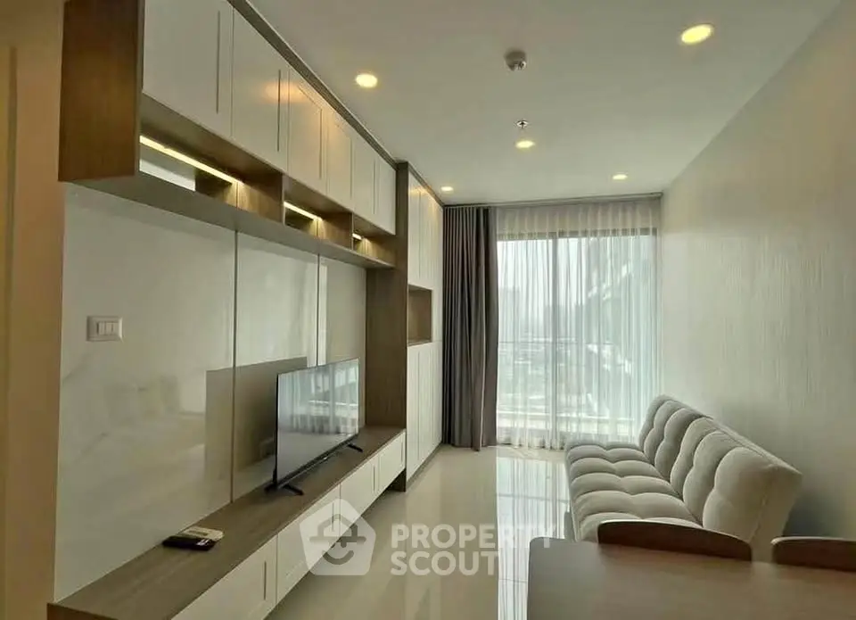 Modern living room with sleek furniture and large window offering natural light.