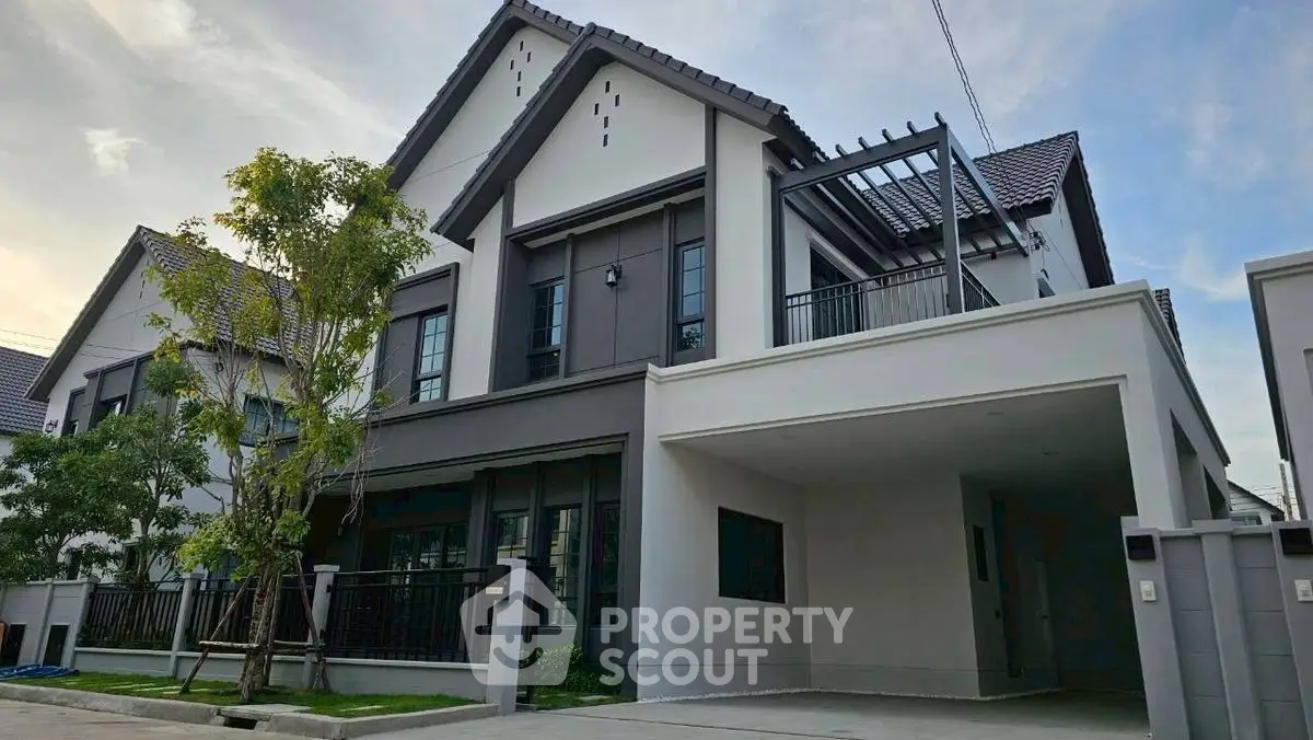 Modern two-story house with sleek design and spacious driveway in suburban neighborhood.