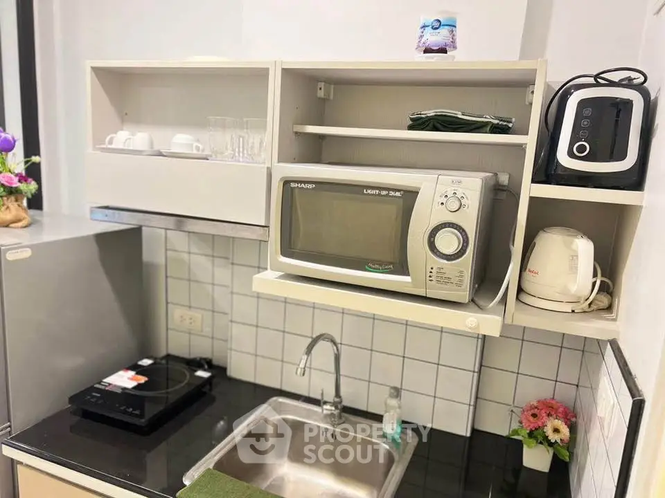 Compact kitchen with microwave, induction cooktop, and modern appliances