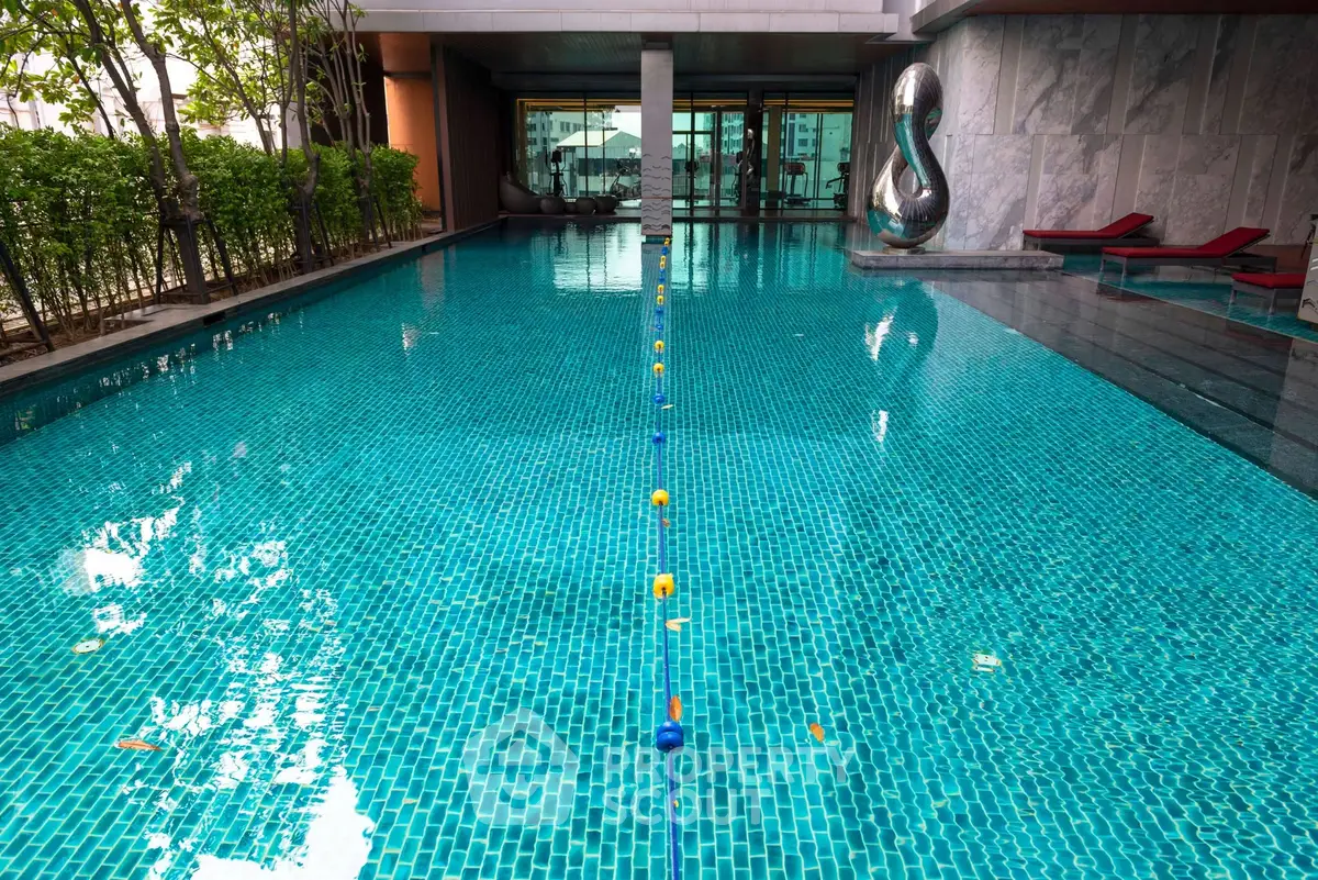 Luxurious swimming pool with modern design and artistic sculpture in upscale residential complex.