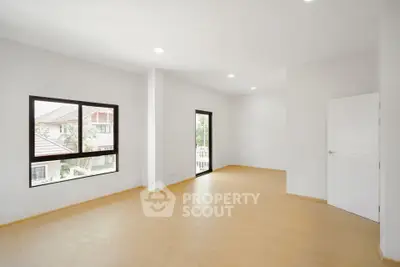 Spacious empty room with large windows and wooden flooring, perfect for customization.