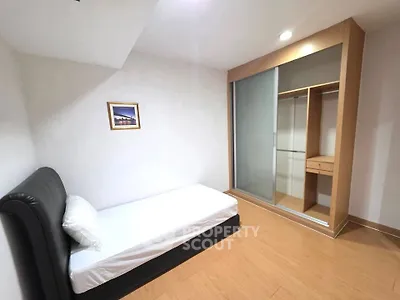 Cozy minimalist bedroom with single bed and built-in wardrobe, perfect for urban living.