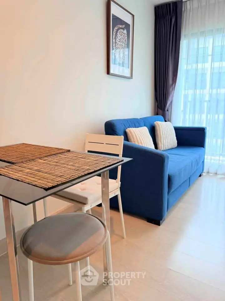 Modern living room with blue sofa and dining area, featuring natural light and stylish decor.