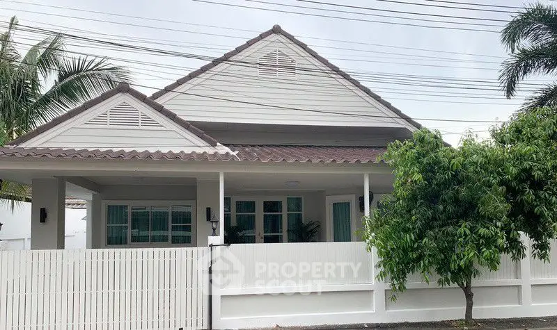 Charming single-story house with a white picket fence and lush greenery, perfect for family living.