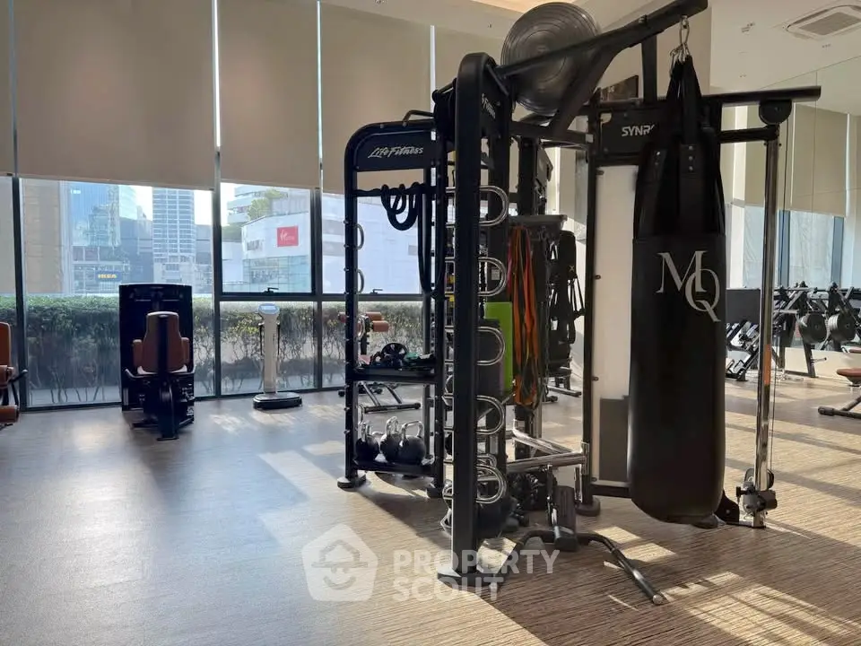 Spacious gym with modern equipment and city view, perfect for fitness enthusiasts.