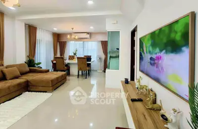 Spacious modern living room with elegant dining area and large TV display.