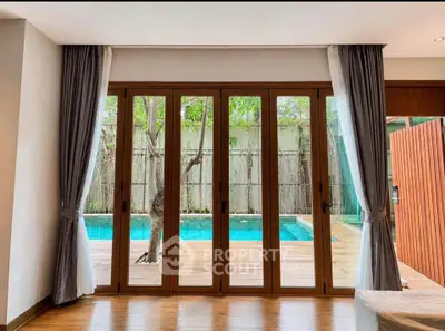 Luxurious living room with pool view through elegant glass doors, perfect for relaxation and entertainment.