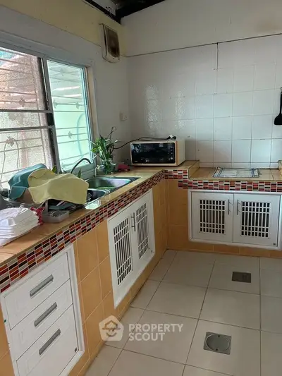 Charming kitchen with tiled countertops and ample storage space, featuring a window for natural light.