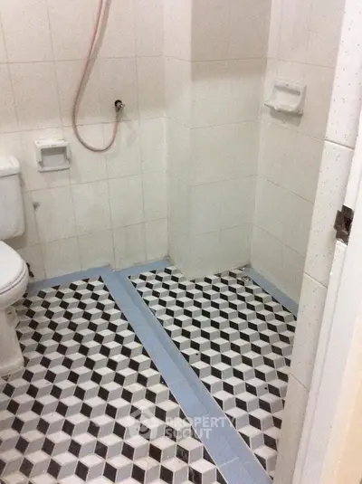 Compact bathroom with geometric tile flooring and simple white fixtures.