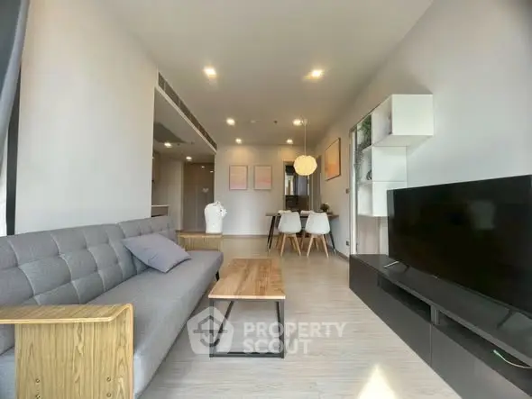 Modern living room with stylish furniture and open layout, featuring a cozy gray sofa and sleek wooden table.
