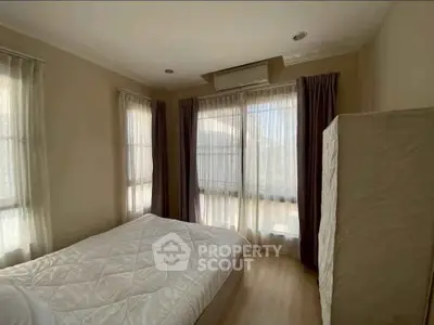 Cozy bedroom with natural light and neutral decor, perfect for relaxation.