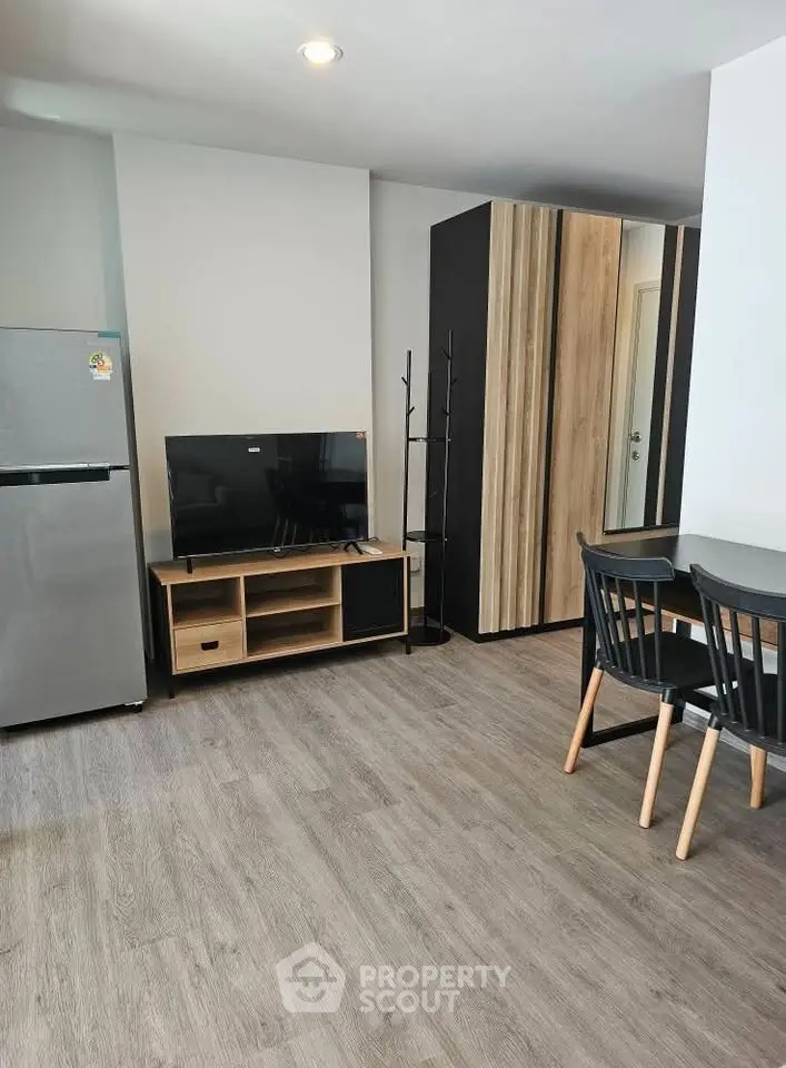 Modern living room with sleek furniture and open layout, featuring a TV and dining area.