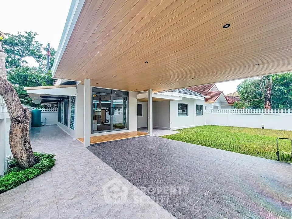 Spacious modern home with covered patio and lush green lawn, perfect for outdoor living.
