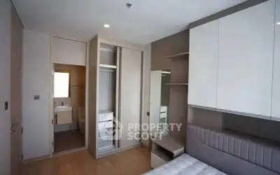 Modern bedroom with built-in wardrobe and ensuite bathroom in stylish apartment.