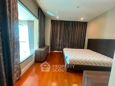 Spacious bedroom with elegant hardwood floors and luxurious drapery in modern apartment.
