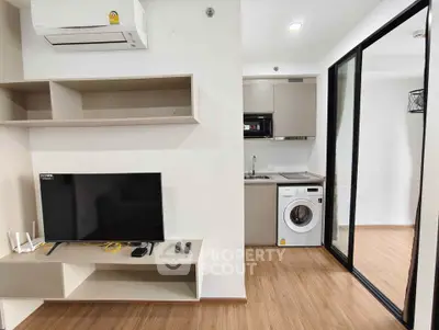 Modern apartment interior with TV, air conditioner, and compact kitchen featuring washing machine.