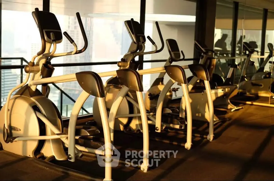 Modern gym with exercise equipment and city view, perfect for fitness enthusiasts.