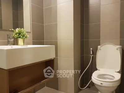 Modern bathroom with sleek fixtures and neutral tiles, featuring a stylish sink and toilet.