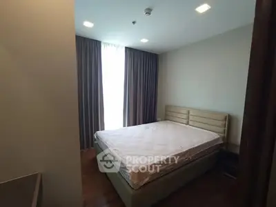 Cozy bedroom with large window and modern furnishings in a stylish apartment.