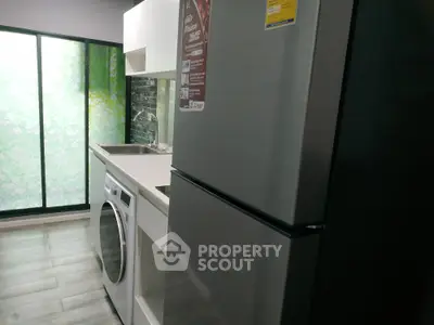 Modern kitchen with sleek appliances and washing machine in compact layout.