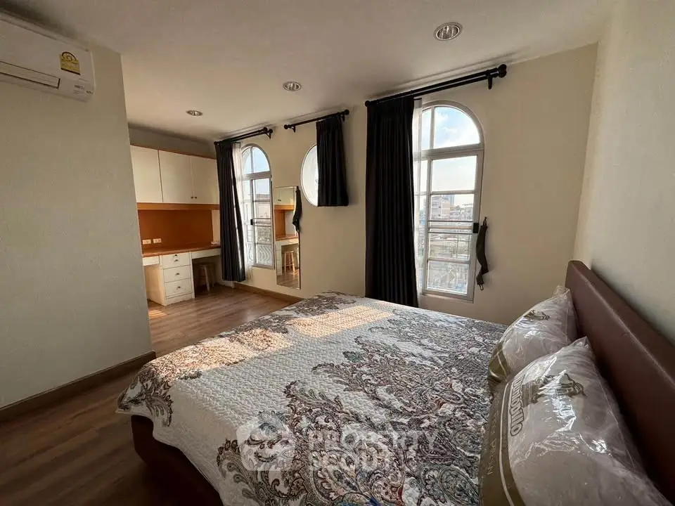 Spacious bedroom with large windows and elegant decor in a modern apartment.