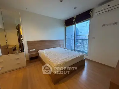Spacious bedroom with wooden flooring and large window in modern apartment.