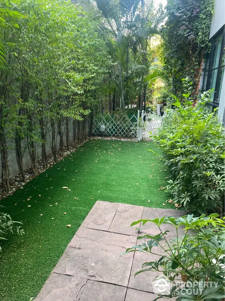 Charming garden with lush greenery and paved pathway, perfect for relaxation and outdoor activities.