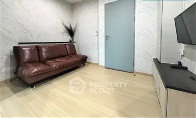 Modern living room with sleek brown leather sofa and mounted TV, featuring minimalist decor and light wood flooring.