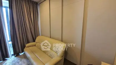 Cozy living room with beige sofa and floor-to-ceiling curtains, perfect for relaxation.