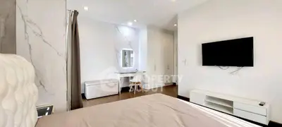 Modern bedroom with wall-mounted TV and stylish vanity in a sleek apartment.