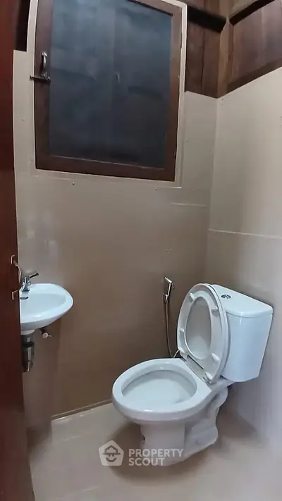 Compact bathroom with toilet and sink, featuring a modern design and neutral tones.