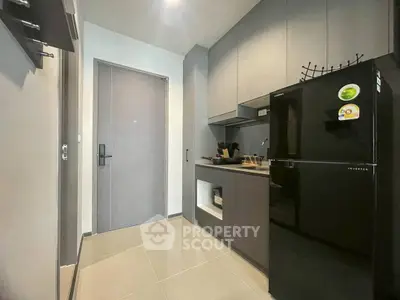 Modern kitchen with sleek black fridge and minimalist cabinetry in compact space.