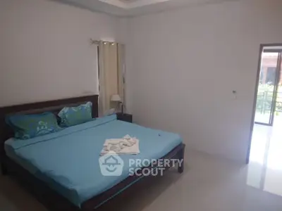 Spacious bedroom with large bed and natural light from window.