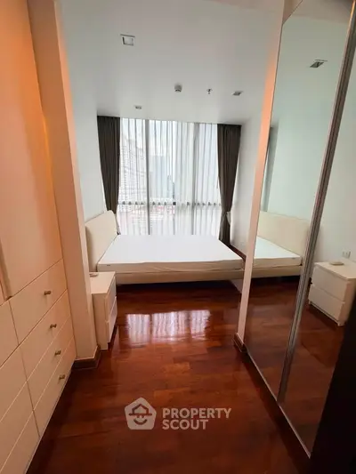 Modern bedroom with floor-to-ceiling windows and hardwood floors in a high-rise apartment.