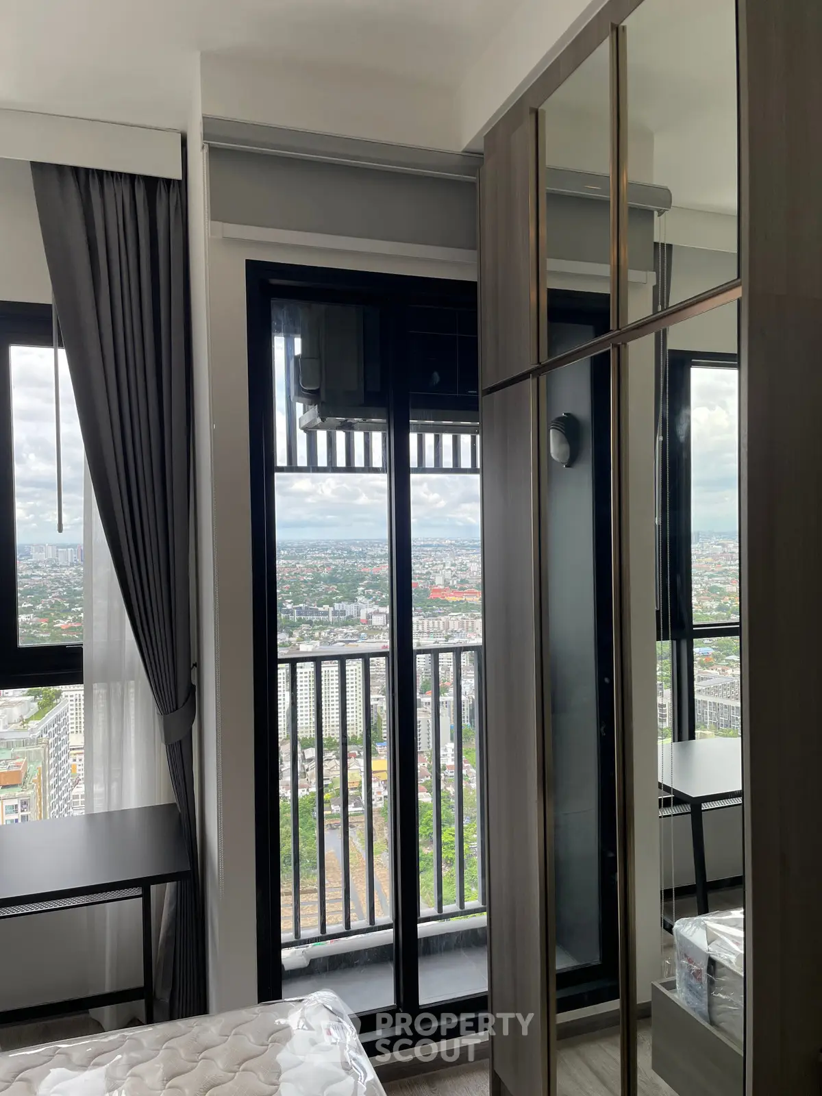 Modern bedroom with balcony offering stunning city view, featuring sleek design and ample natural light.