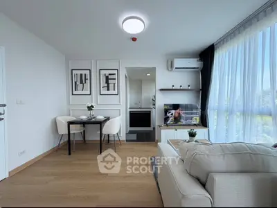 Modern living room with cozy sofa, dining area, and natural light from large windows.
