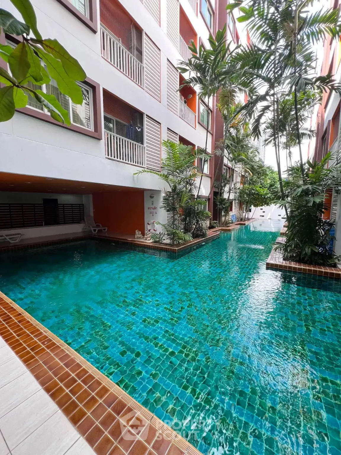Luxurious residential building with a stunning outdoor pool surrounded by lush greenery.