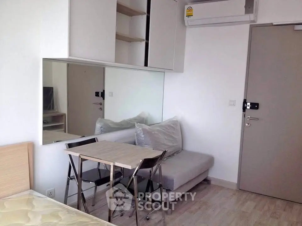 Modern compact living room with sofa, dining table, and air conditioning in a cozy apartment.